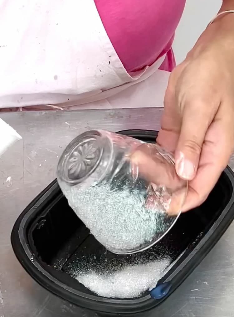 tapping off excess glitter from glass candle holder